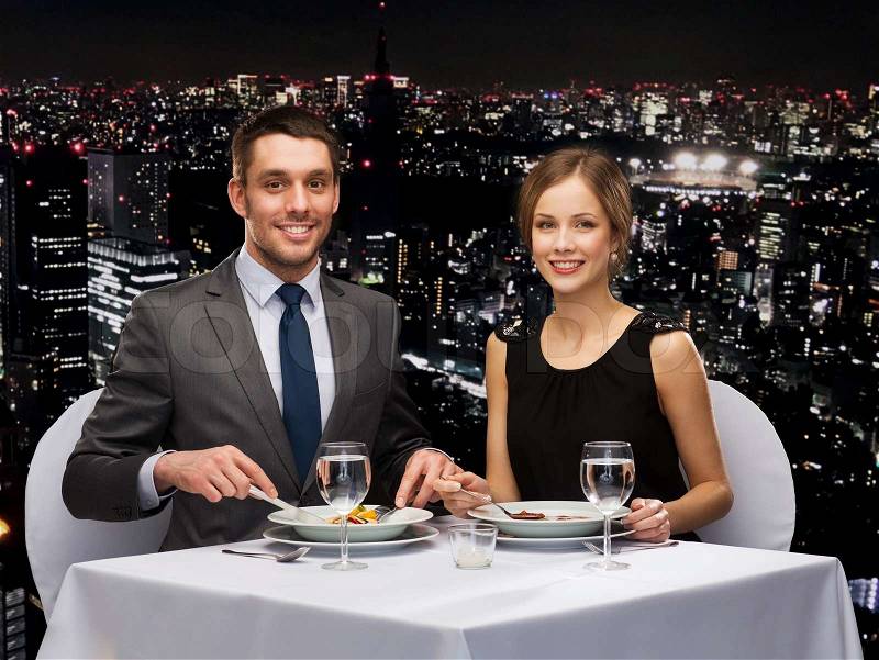 Restaurant, couple and holiday concept - smiling couple eating main course at restaurant, stock photo