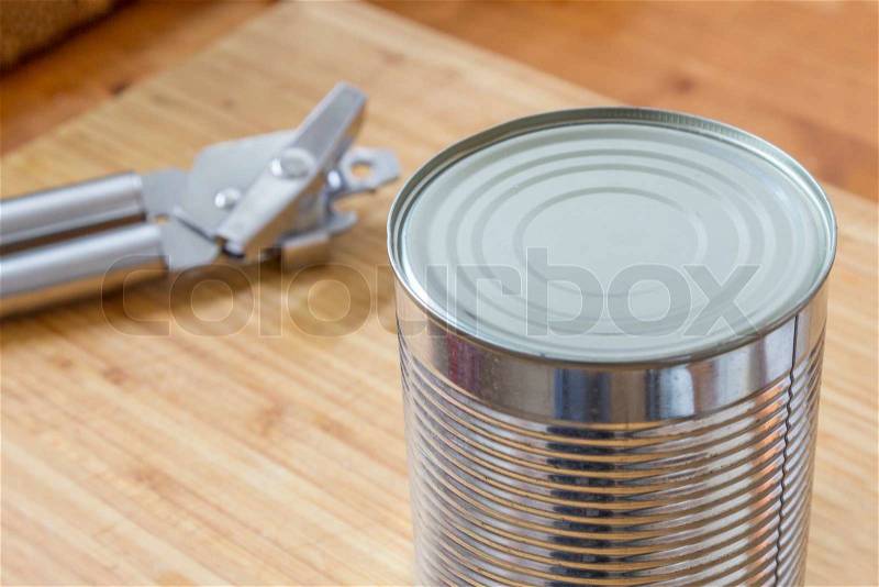 A Silver Can with a can opener on a wooden table in the kitchen, stock photo