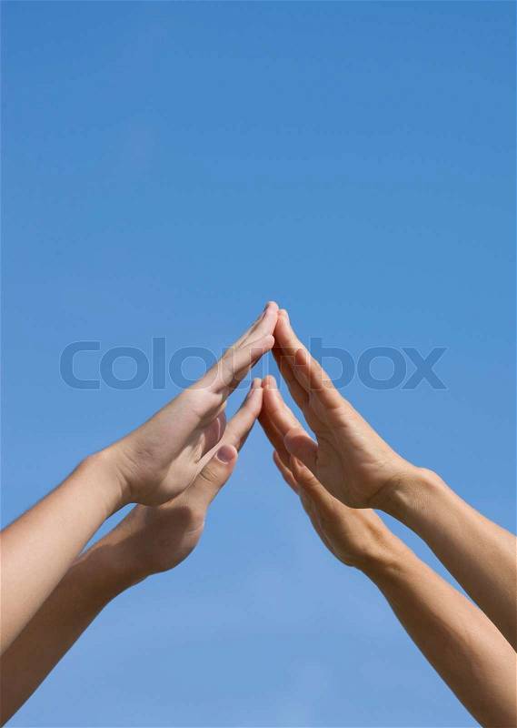 Two pairs of hands raised over the blue skies, stock photo