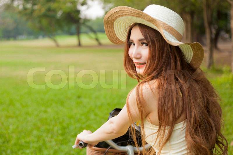 Woman riding a bicycle. Woman with hat riding a bicycle in the park, stock photo