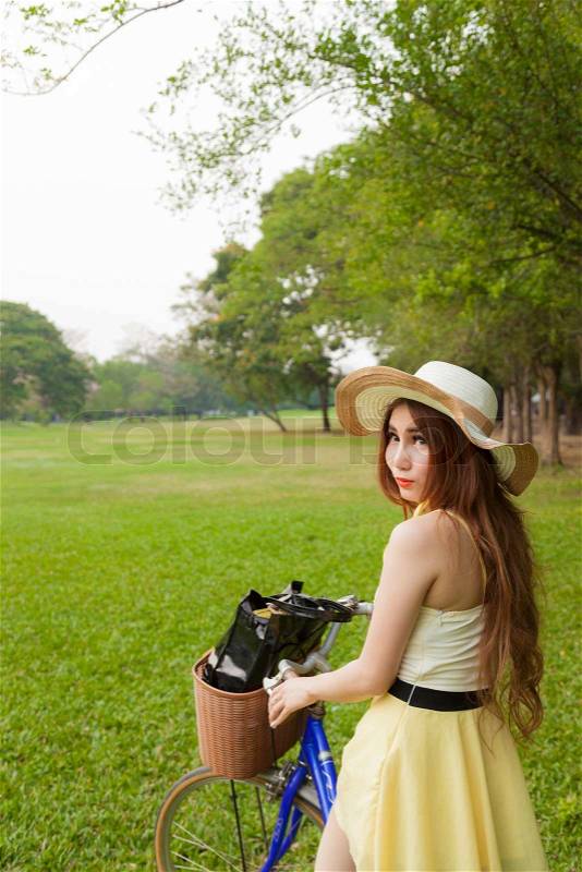 Woman riding a bicycle. Woman with hat riding a bicycle in the park, stock photo