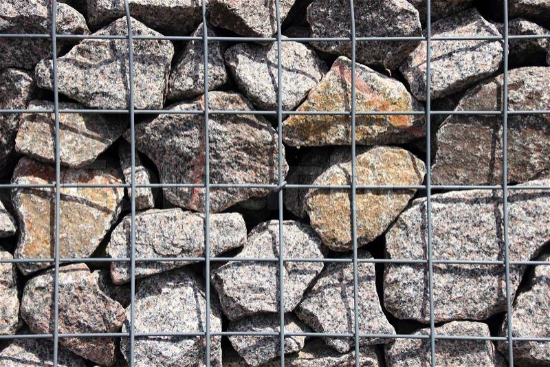 Rocks in solid metal grid wall closeup background, stock photo