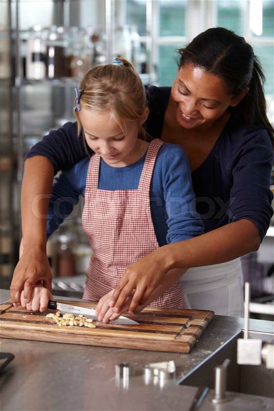 A baker teaching a girl how to chop nuts, stock photo