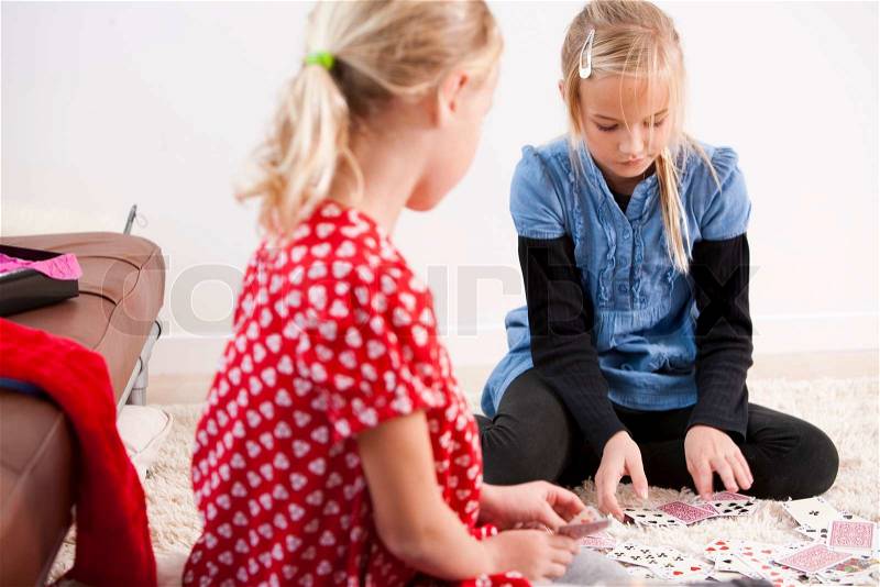 Two girls playing cards on the floor, stock photo