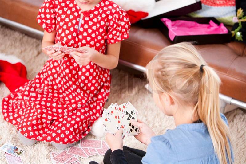 Two young girls playing cards on the floor on Christmas day, stock photo