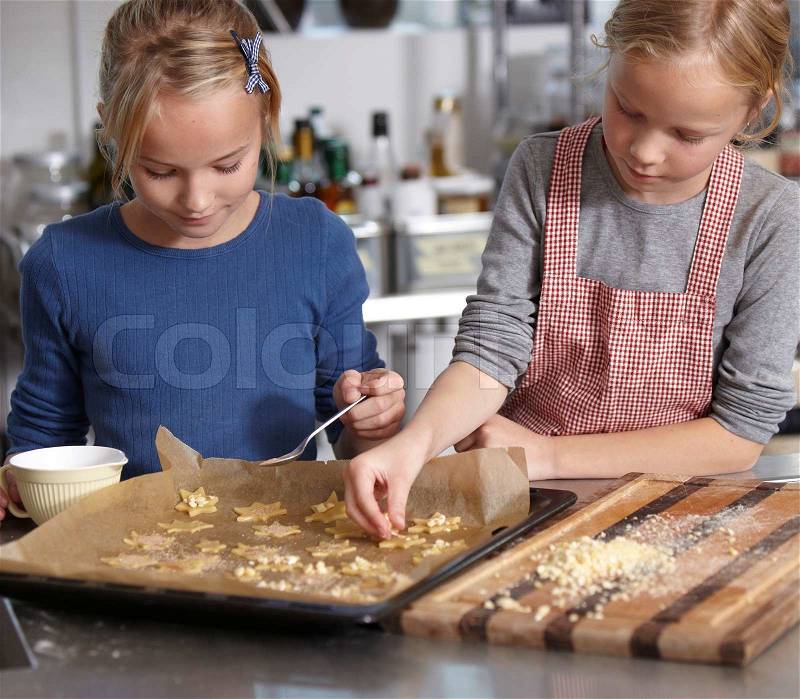 Two sisters making Christmas cookies, stock photo