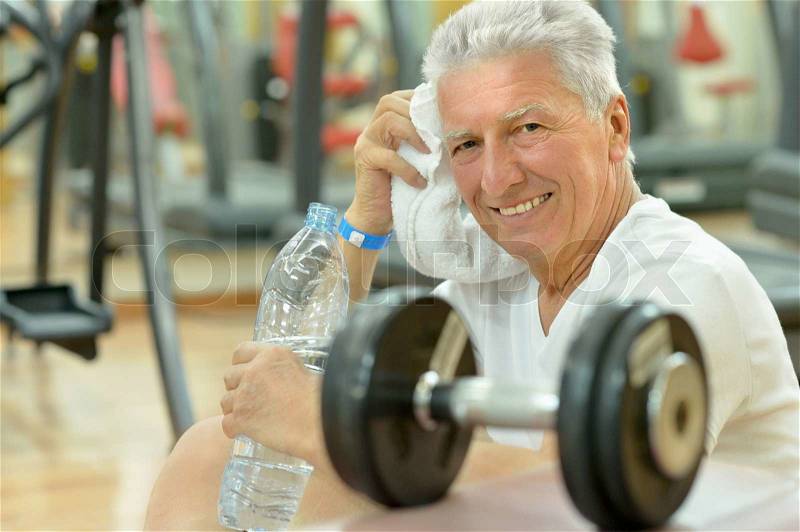 Elderly man in a gym. exercising with dumbbells, stock photo