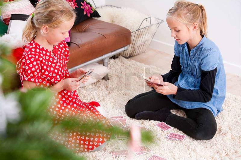 Girls playing cards while sitting on the floor, stock photo