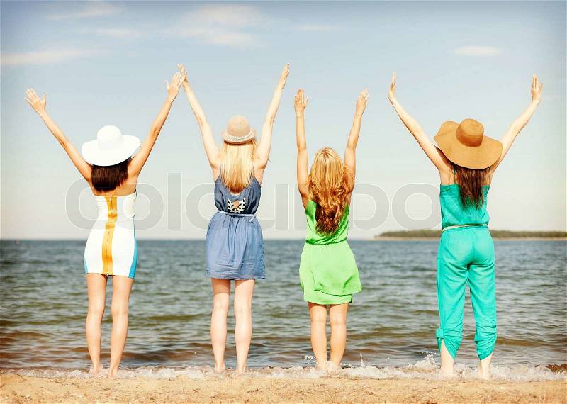 Summer holidays and vacation concept - girls with hands up on the beach, stock photo