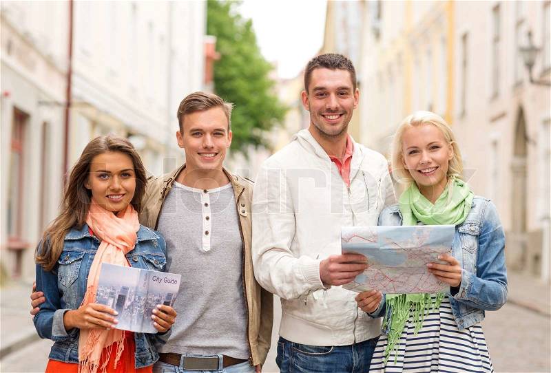 Travel, vacation and friendship concept - group of smiling friends with city guide and map exploring city, stock photo