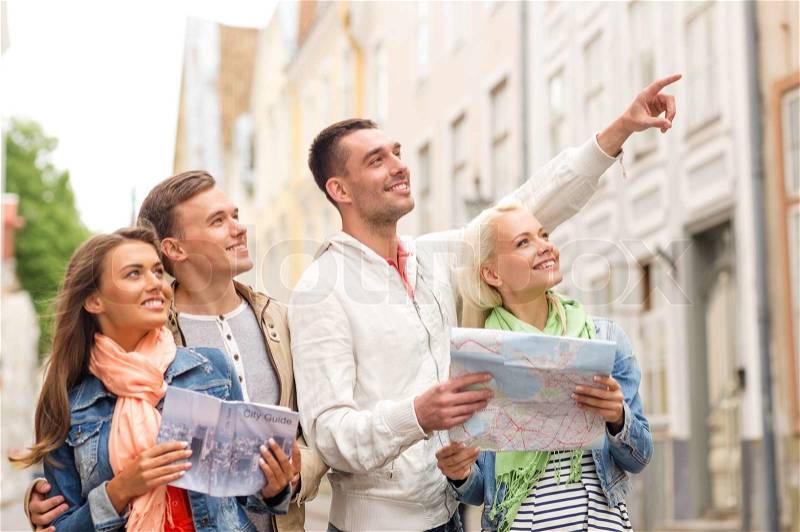 Travel, vacation and friendship concept - group of smiling friends with city guide and map exploring city, stock photo