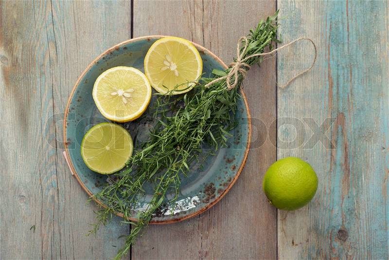 Fresh tarragon with lemon and lime on wooden background, stock photo