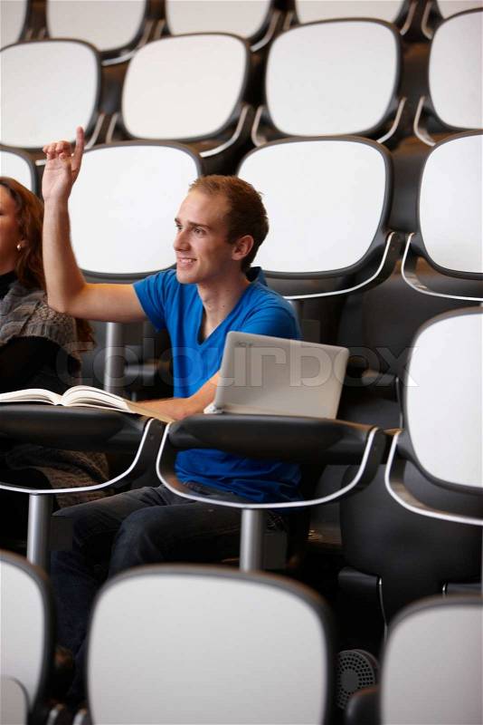 A male college student raising his hand to ask a question, stock photo