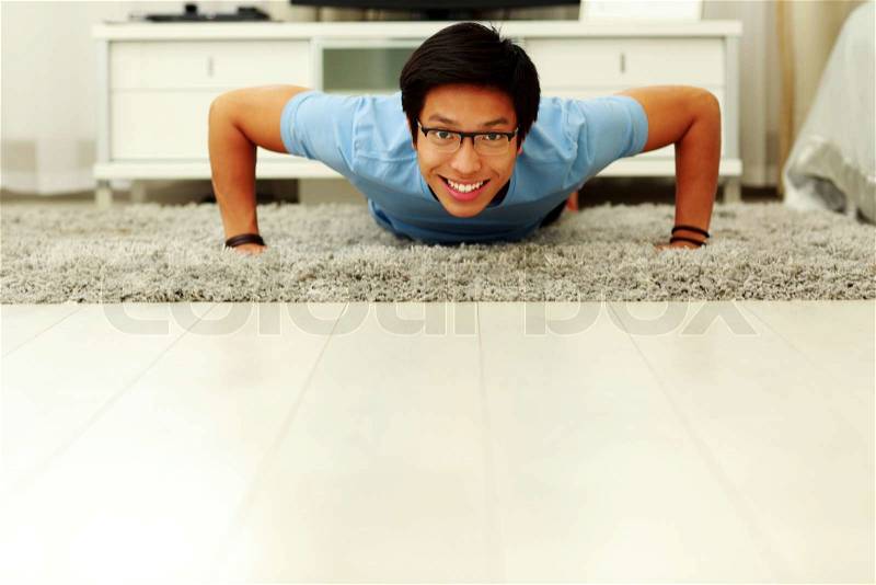 Portrait of a sporty young man doing push ups in the living room at home, stock photo