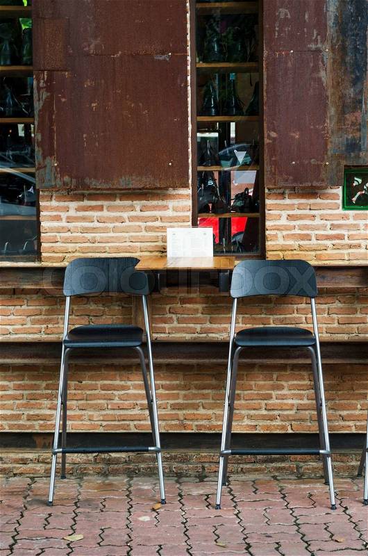 Two cafe chairs against brick wall, vintage cafeteria, stock photo