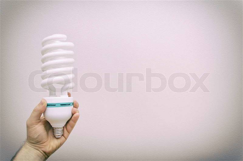 Hand holding big energy efficient spiral-shaped fluorescent lamp, stock photo