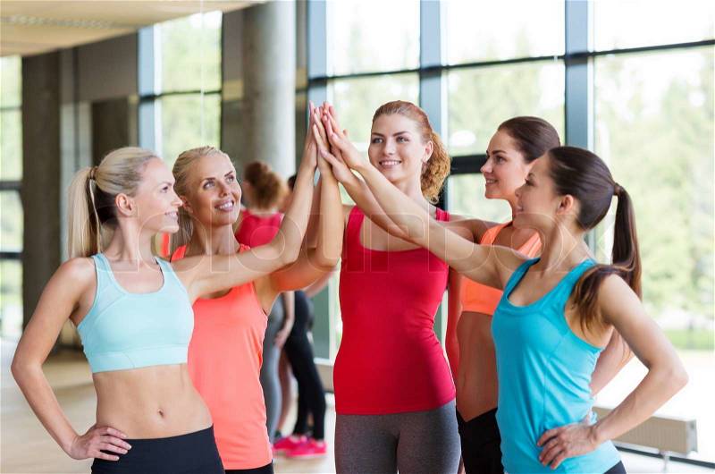 Fitness, sport, friendship and lifestyle concept - group of women making high five gesture in gym, stock photo