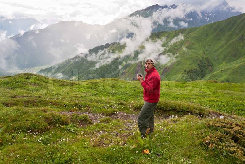 Happy hiker relaxing iwth a cup of tea in mountains, stock photo