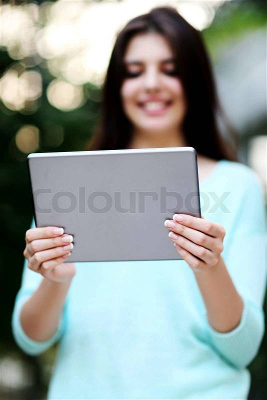 Portrait of a woman holding tablet computer. Focus on tablet computer, stock photo