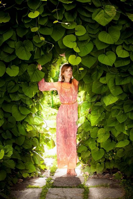 Beautiful romantic woman posing at floral arch at garden, stock photo