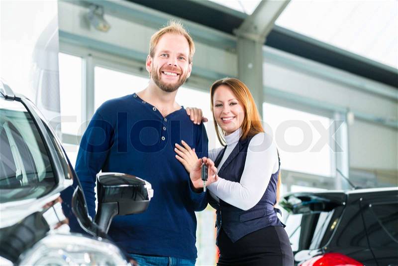 Young couple or customers in car dealership they bought a auto or new car, stock photo