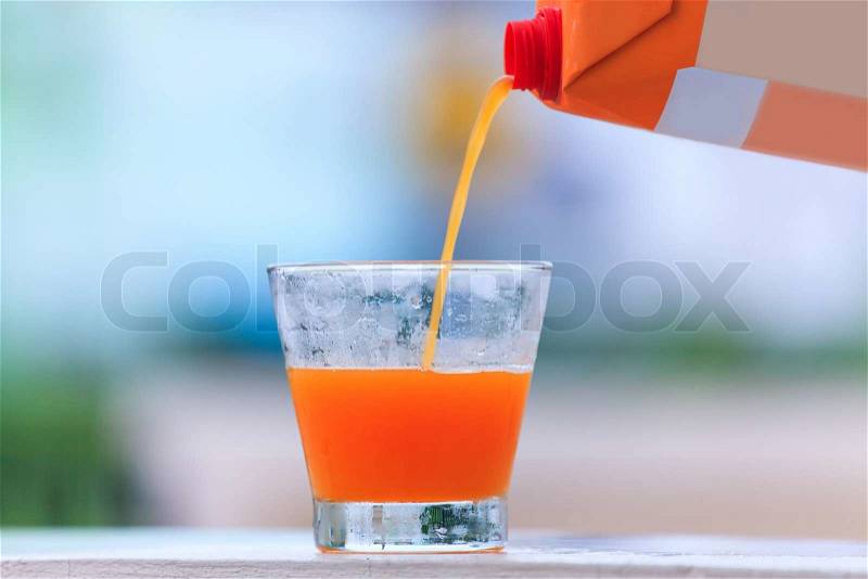 Pouring orange juice on glass, stock photo