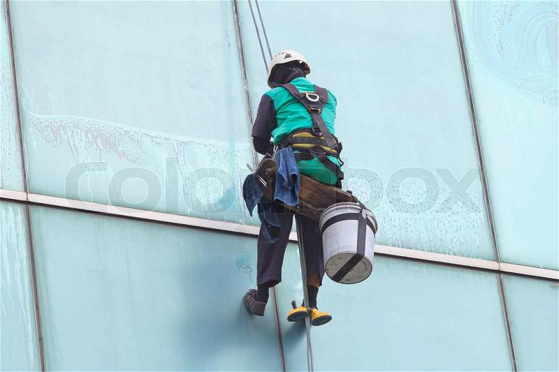 A worker cleaning windows service on high rise building, stock photo