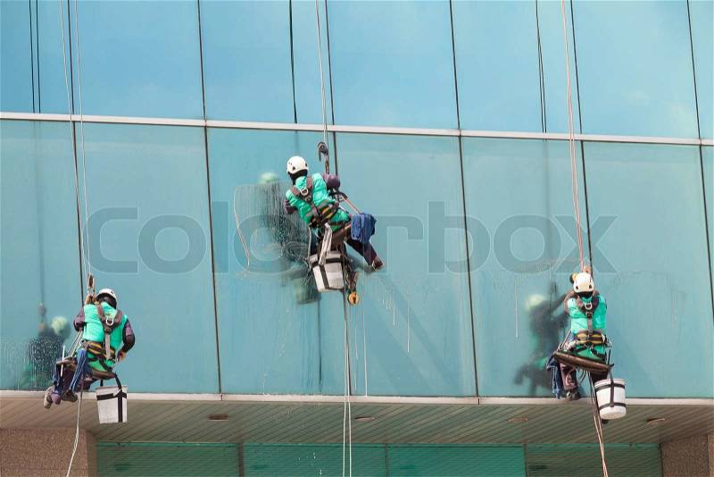 Group of workers cleaning windows service on high rise building, stock photo