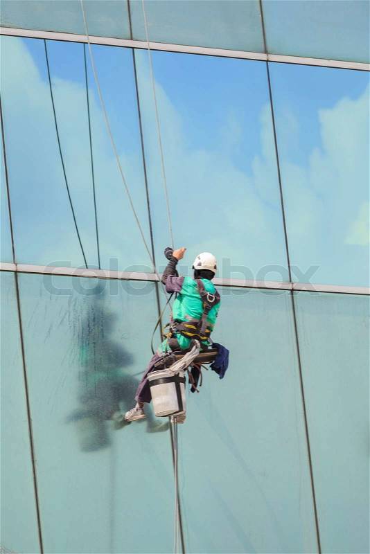 A worker cleaning windows service on high rise building, stock photo