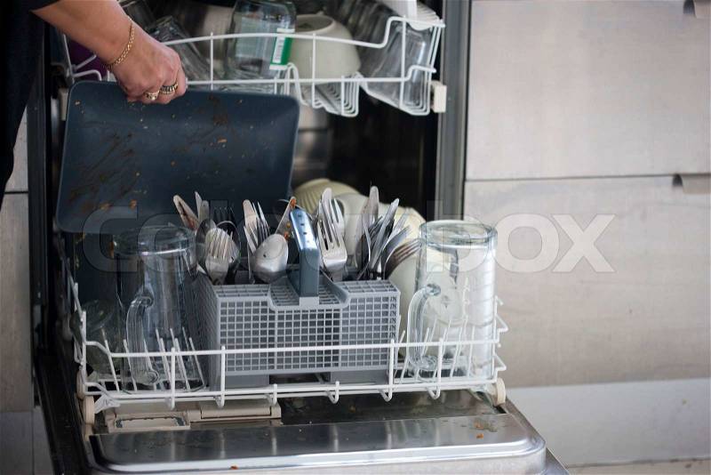 A woman putting dirty kitchen wares in the dishwasher, stock photo