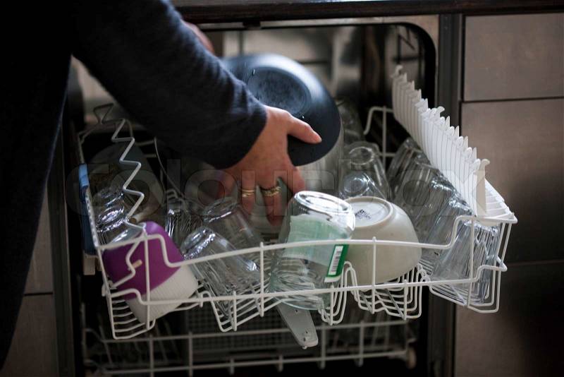 A woman putting dirty kitchen wares in the dishwasher, stock photo