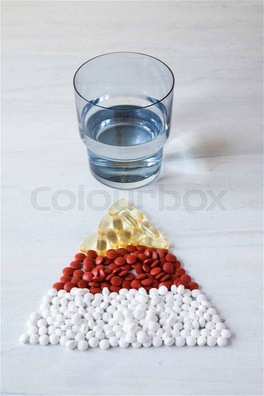 Pyramid of vitamin supplements and a glass of water, stock photo