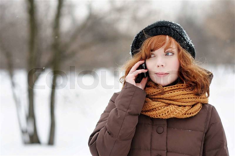 Outdoors portrait of young beautiful woman with mobile in winter , stock photo