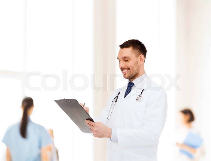 Medicine, profession, and healthcare concept - smiling male doctor with clipboard and stethoscope writing prescription over white background, stock photo
