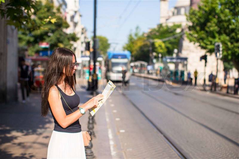 Young beautiful traveling woman with map of city in hands, stock photo