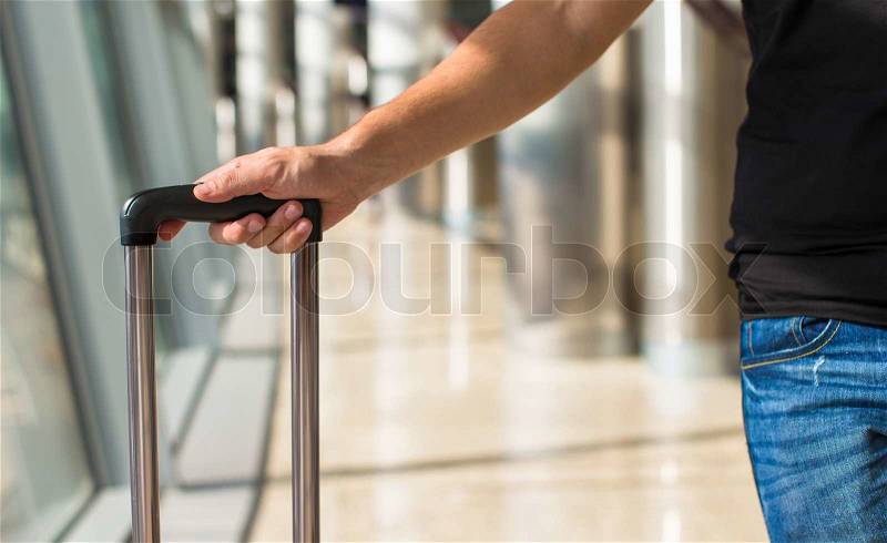 Close-up of a man with luggage in airport while waiting the flight, stock photo