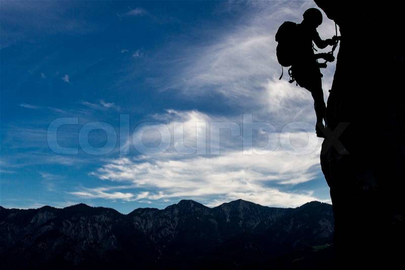 Silhouette of a climber high above mountains, stock photo