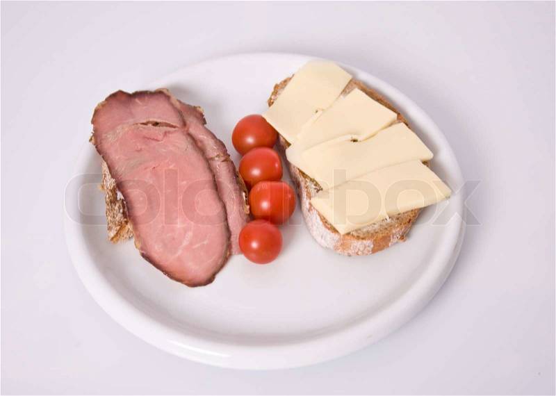 Top image of a plate with tomatoes and bread topped with ham and cheese, stock photo
