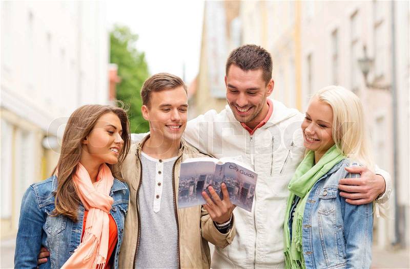 Travel, vacation and friendship concept - group of smiling friends with city guide exploring town, stock photo