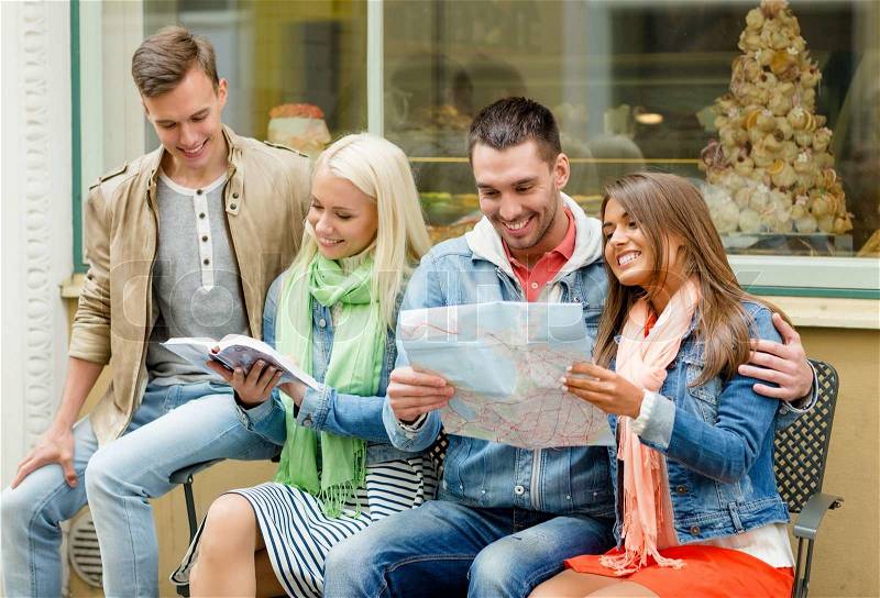 Travel, vacation and friendship concept - group of smiling friends with city guide and map exploring town, stock photo