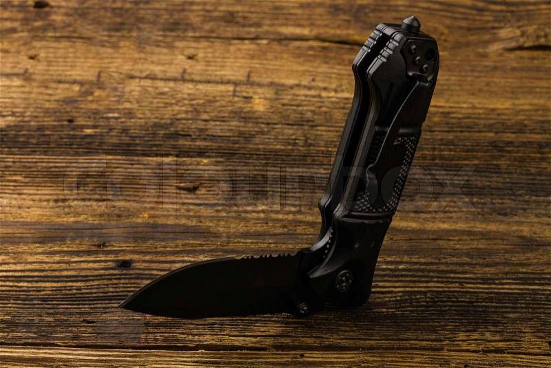 Folding pocket knife with one edge on wooden background, stock photo
