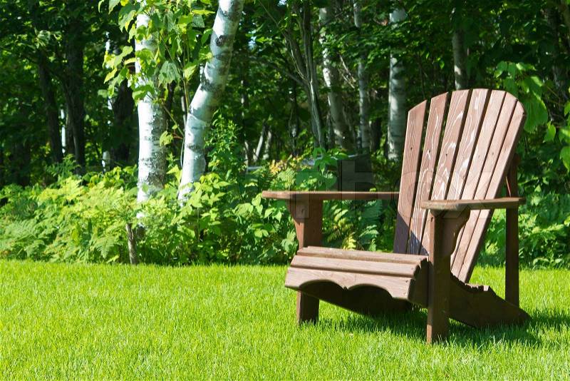 Wooden Adirondack summer lawn chair outside on the green grass, stock photo
