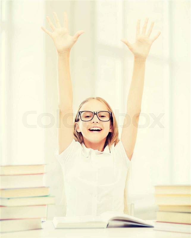 Education and school concept - little student girl with books and hands up at school, stock photo