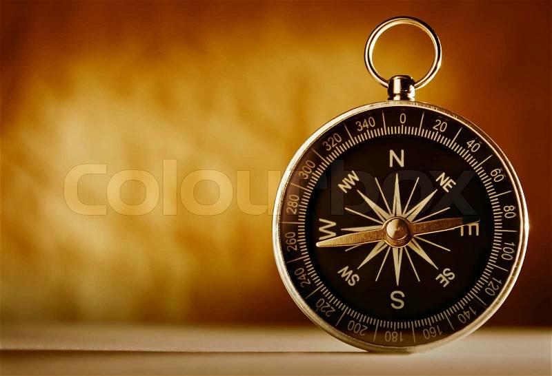 Magnetic compass against an old brown vintage background with a highlight and copyspace in a conceptual image of navigation, adventure and travel, stock photo
