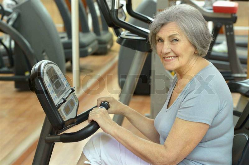 Cute smiling senior woman exercising in gym, stock photo