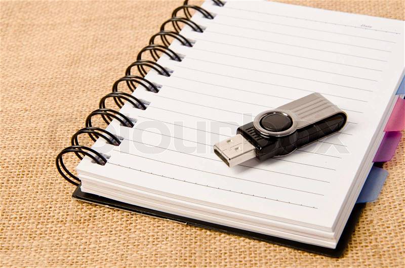 Open diary ring binder and Flash drive on sack background, stock photo