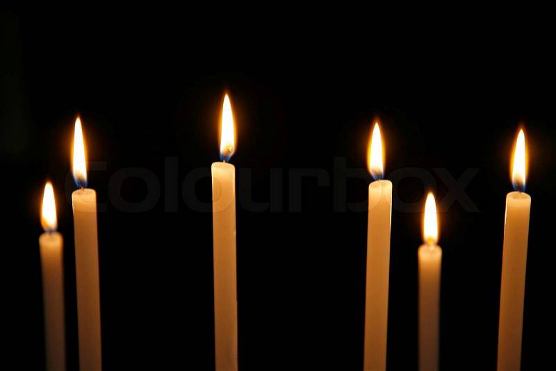 Candles in Roman Catholic church. Focus on flame number three from left. Natural lightening. Shallow DOF, stock photo