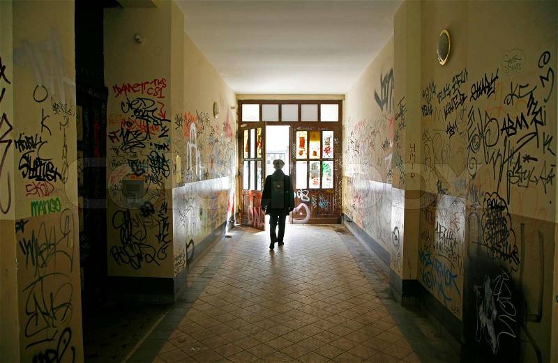 Woman leaving corridor with lots of graffiti in Prenzlauer Berg - Berlin - Germany. Motion blur, stock photo