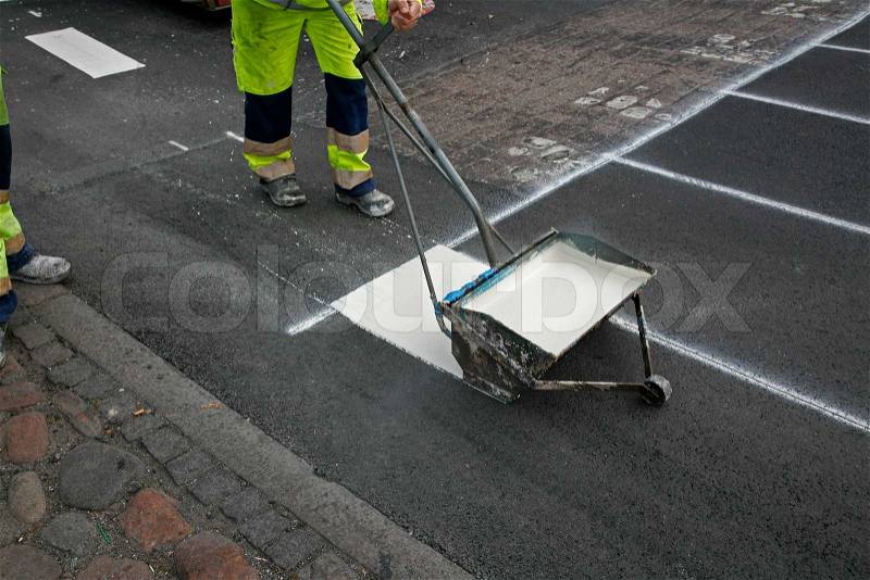 Worker painting new stripes on a cross walk, stock photo