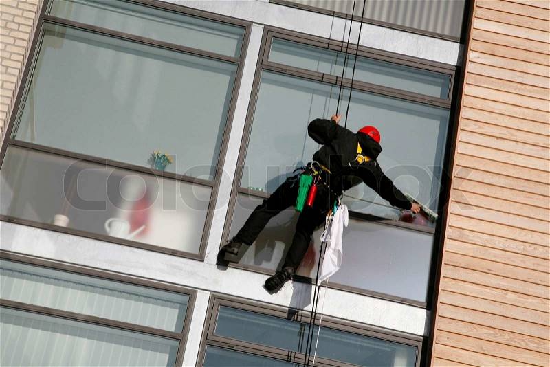 Climber on job as windows cleaner in a quiet new apartment building by the waterfront of Nyborg, Denmark, stock photo